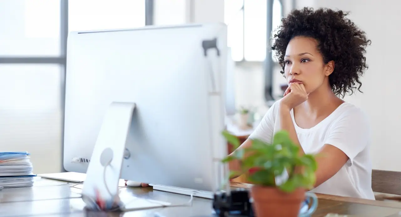 Une recruteuse attentive devant son écran d'ordinateur, concentrée sur la rédaction d'une offre d'emploi.