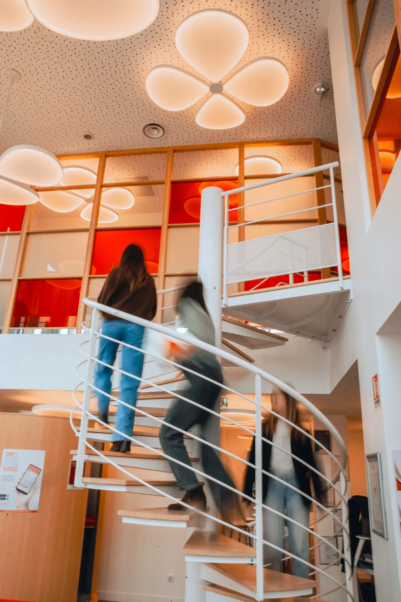 Des collaborateurs s'activent dans l'escalier en colimaçon d'une agence Actual moderne et lumineuse.