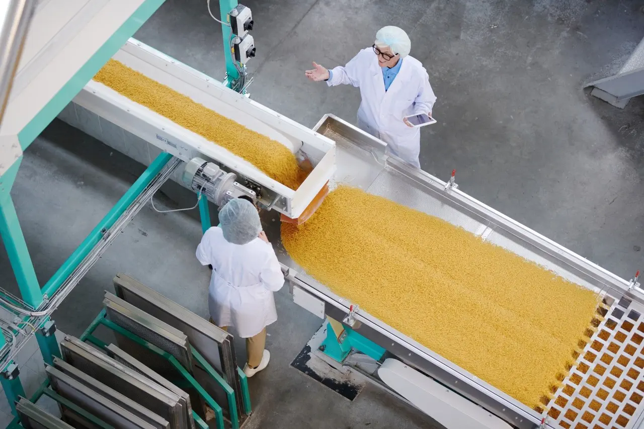 Deux professionnels de l'agroalimentaire contrôlant une ligne de production industrielle.