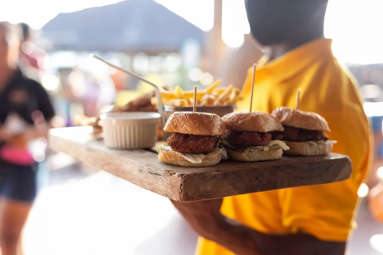 Serveur portant un plateau de mini-burgers et frites pour un job étudiant en restauration.