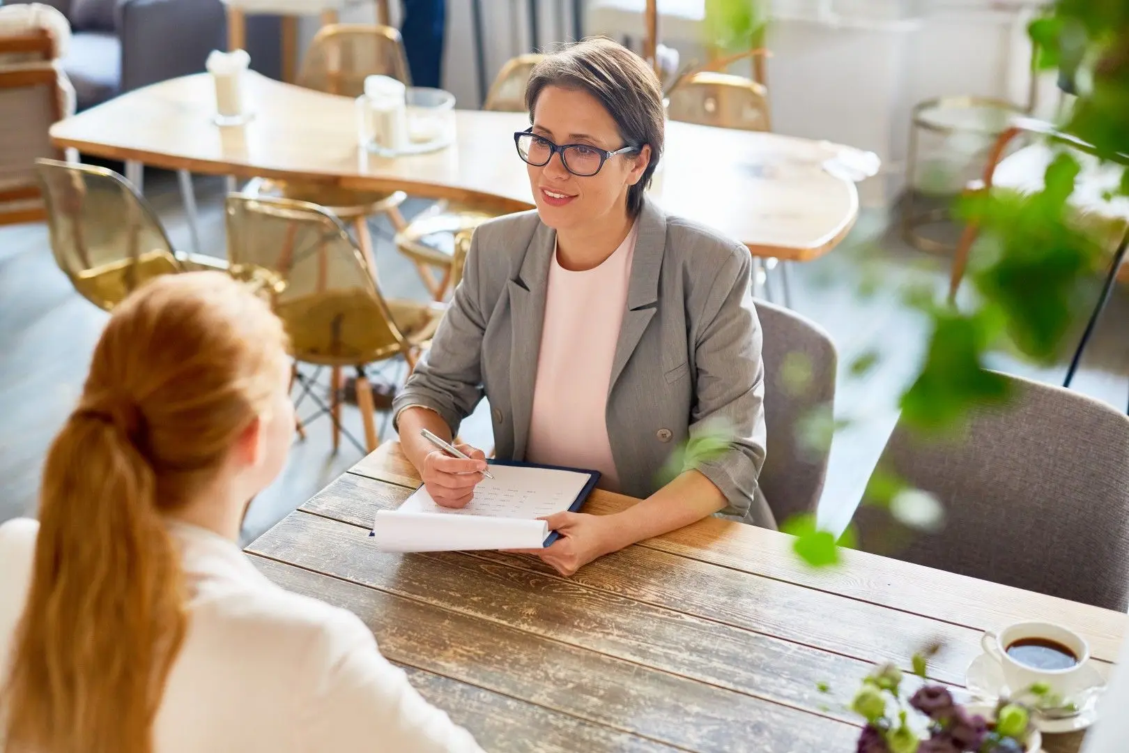 Une recruteuse prend des notes face à une candidate lors d'un entretien d'embauche.