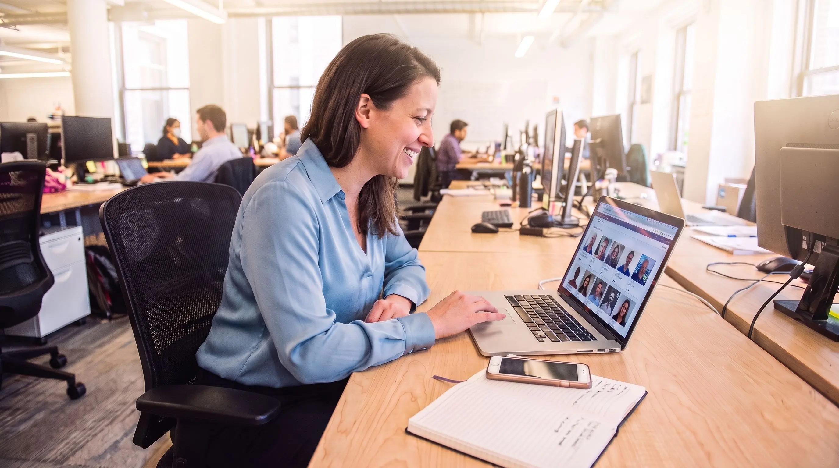Une recruteuse consulte des profils de candidats sur son ordinateur portable dans un bureau en open space.