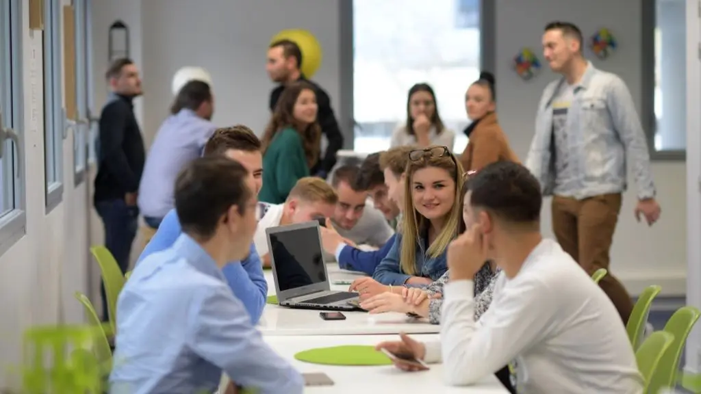 Des étudiants travaillent en groupe autour d'un ordinateur portable lors d'une formation.