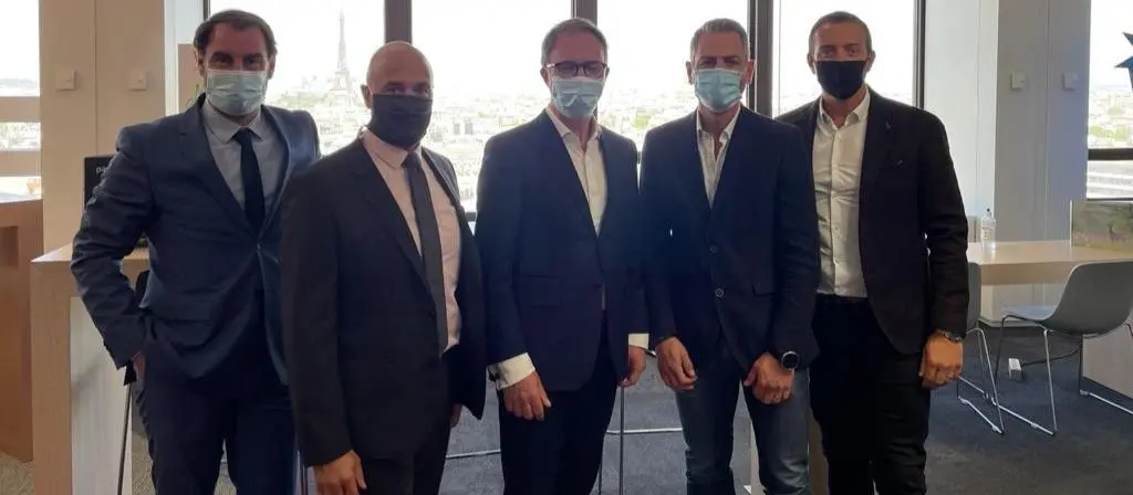 Cinq collaborateurs de CCLD, filiale d'Actual, posent en costume et masque devant une vue de Paris.