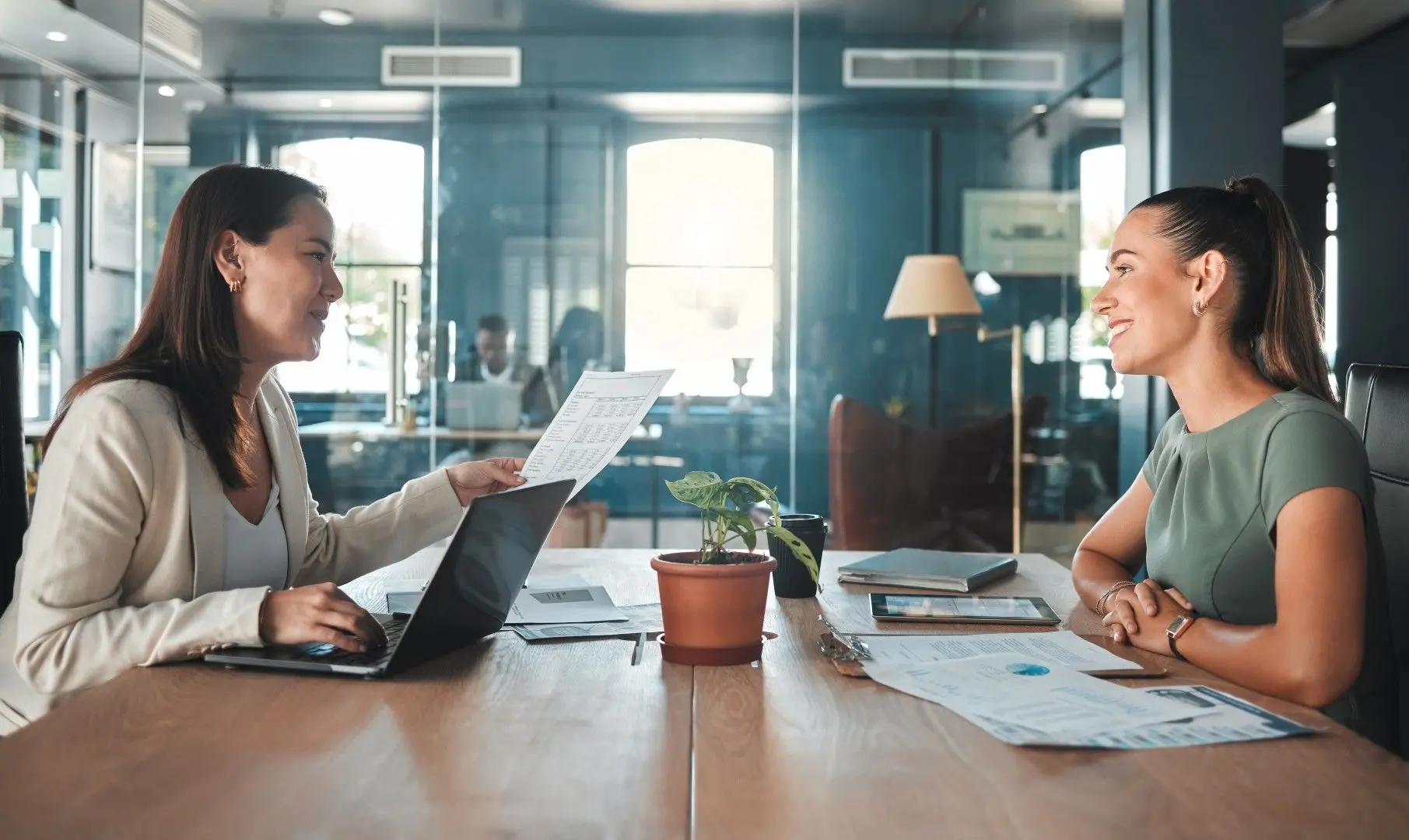 Une candidate et une recruteuse échangent avec le sourire lors d'un entretien d'embauche dans un bureau.