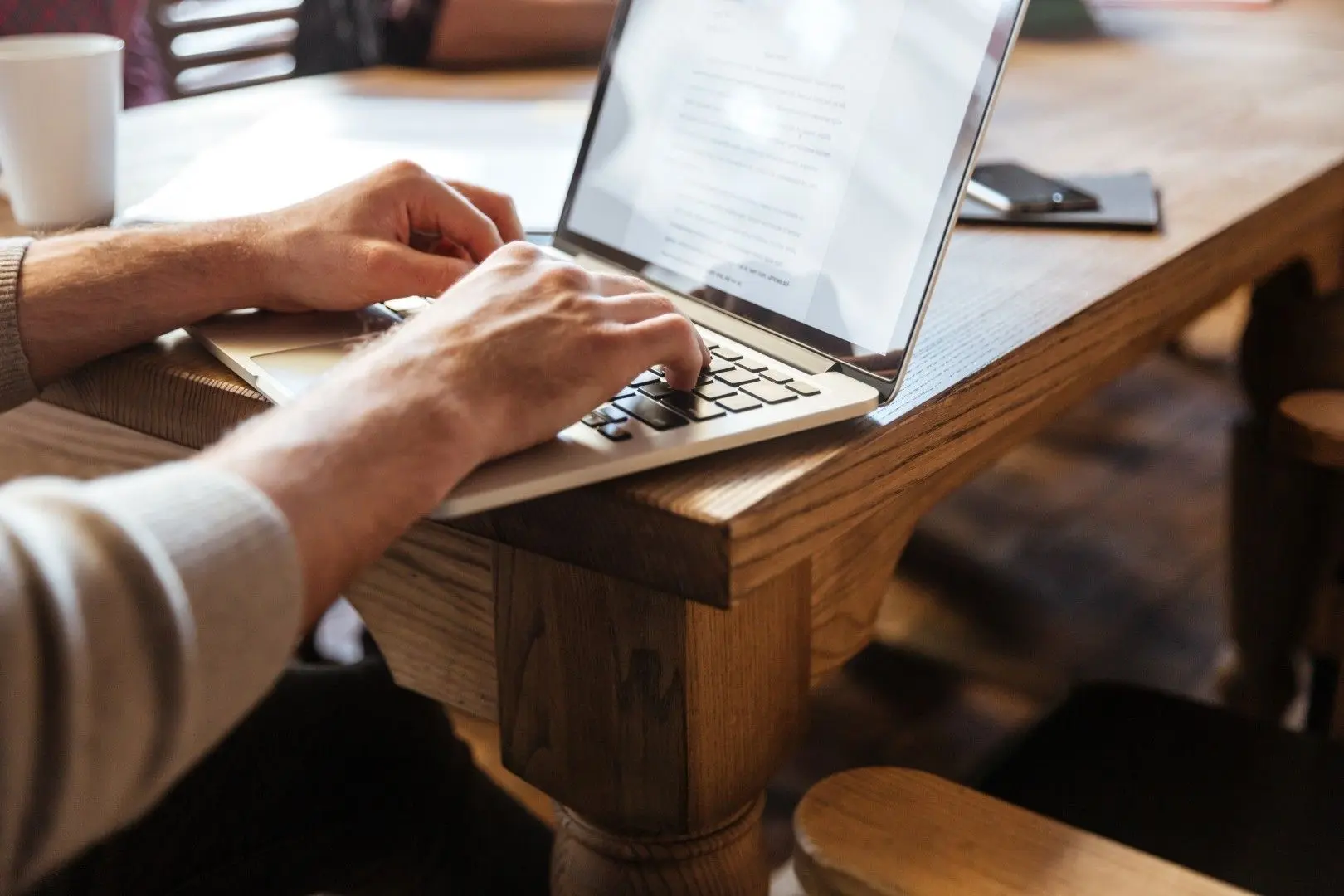 Une personne écrit sur le clavier d'un ordinateur portable posé sur une table.