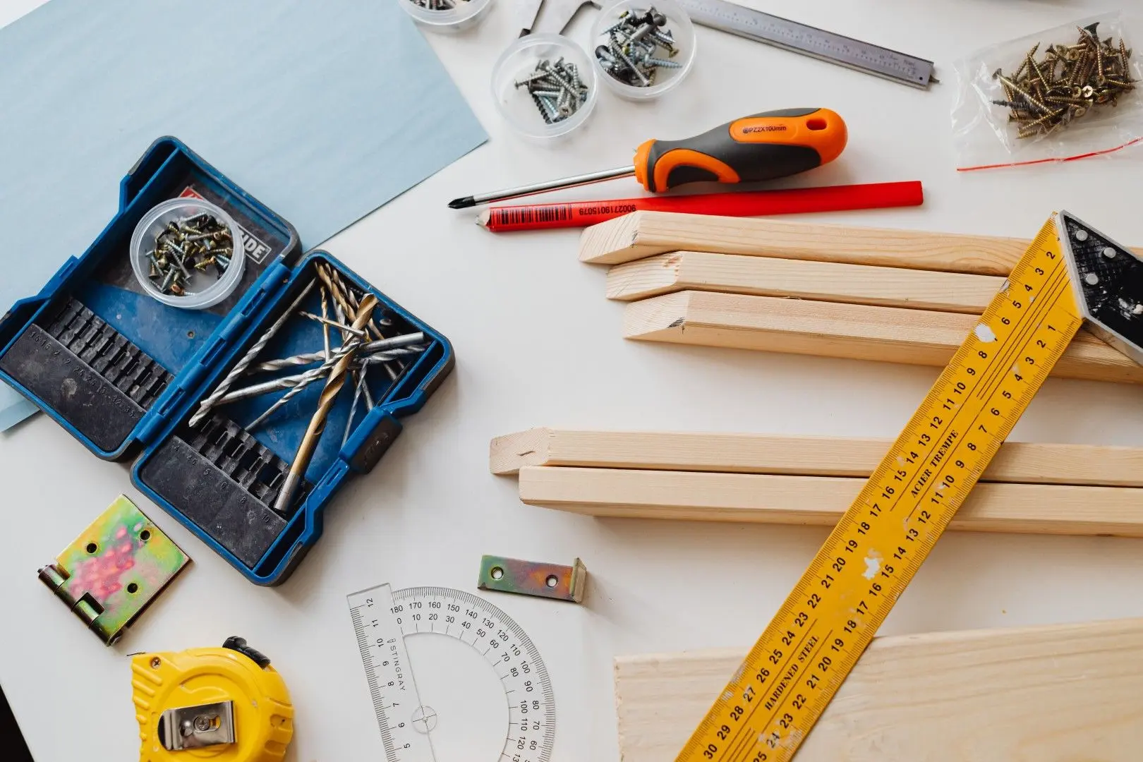 Outils de bricolage, vis et morceaux de bois disposés sur une table pour des travaux manuels.