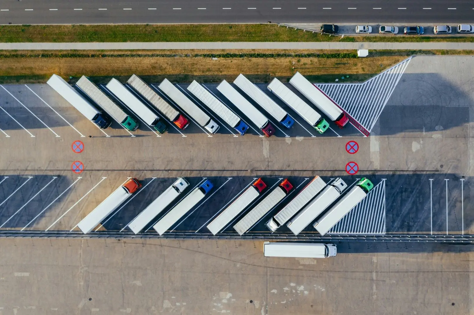 Vue aérienne de camions alignés sur le parking d'une plateforme logistique.