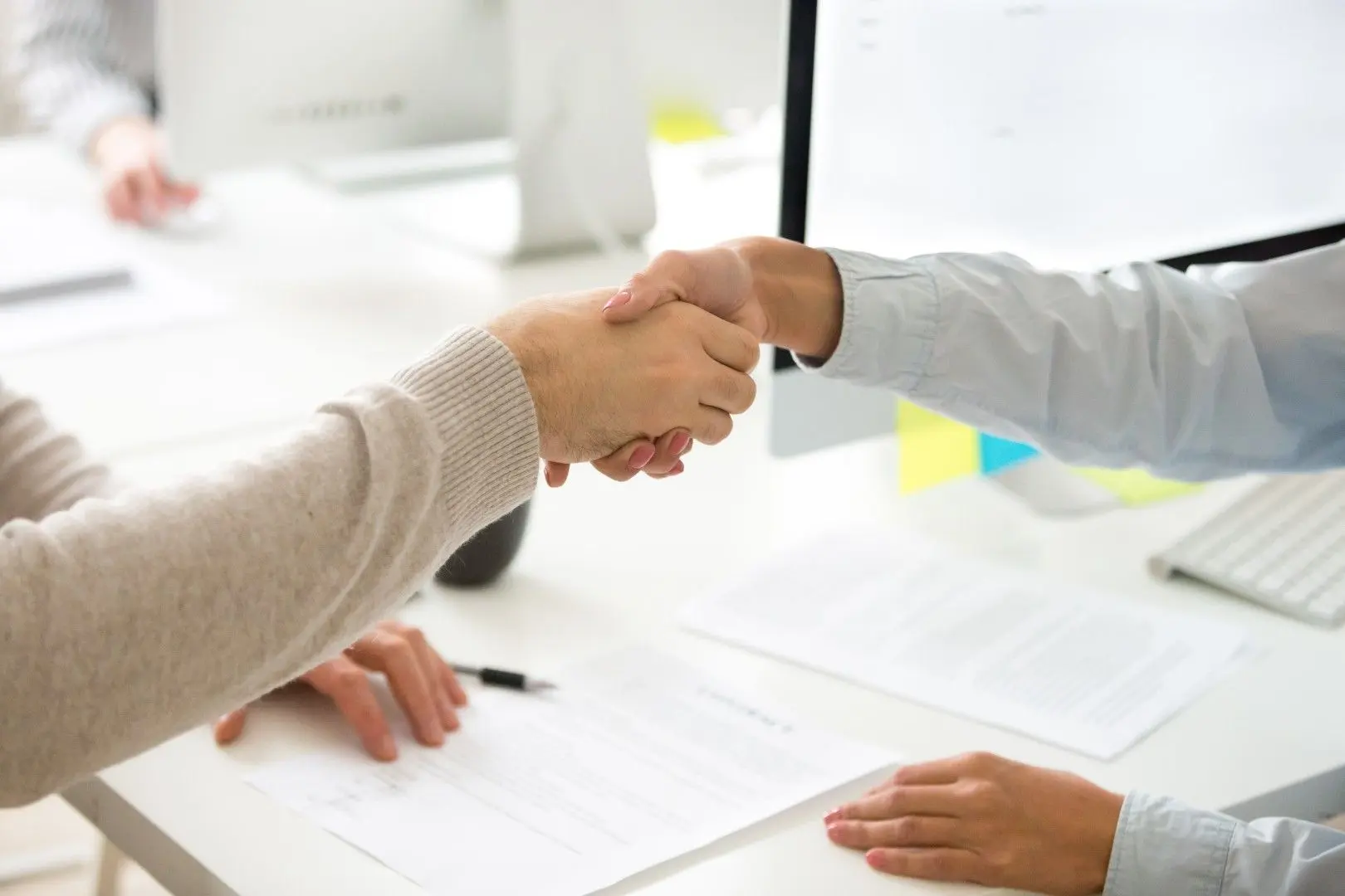 Poignée de main entre un employeur et un salarié au-dessus d'un contrat de travail.