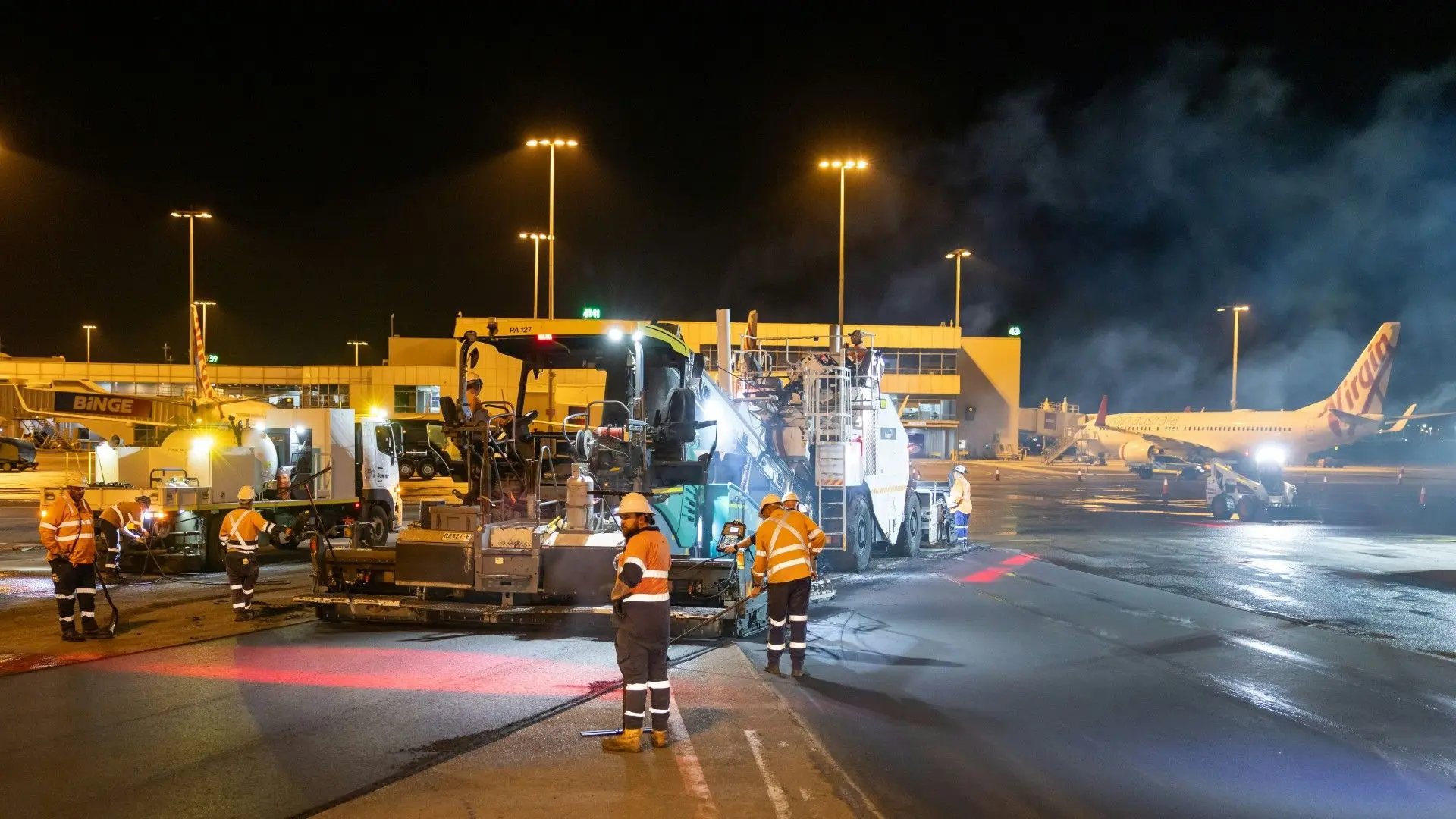 Des ouvriers effectuant des travaux de nuit sur la piste d'un aéroport.