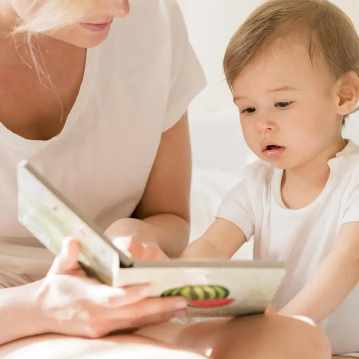 Une professionnelle de la petite enfance lit un livre avec un enfant pour créer un lien de confiance.