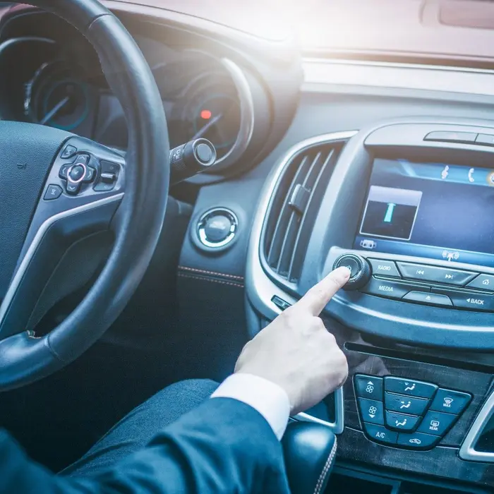 Un professionnel en costume règle les commandes de sa voiture lors d'un déplacement professionnel.