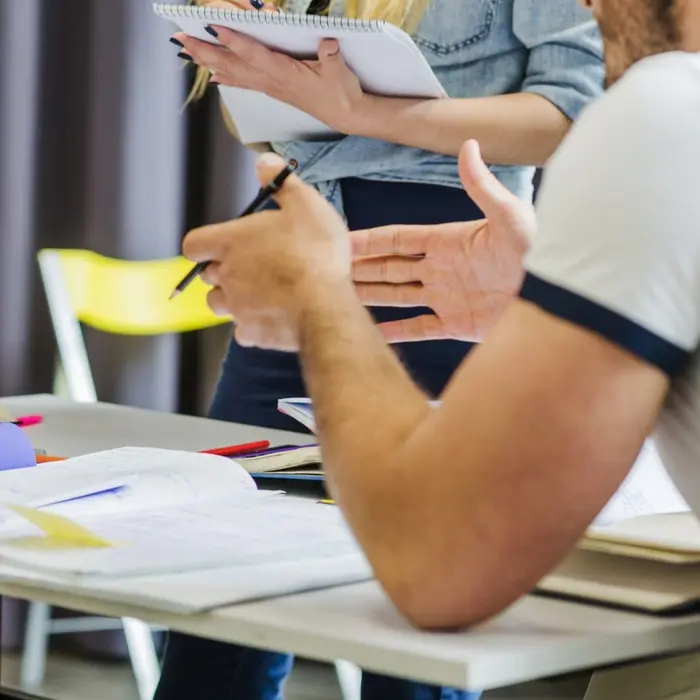 Échange et prise de notes entre collaborateurs durant une séance de formation.
