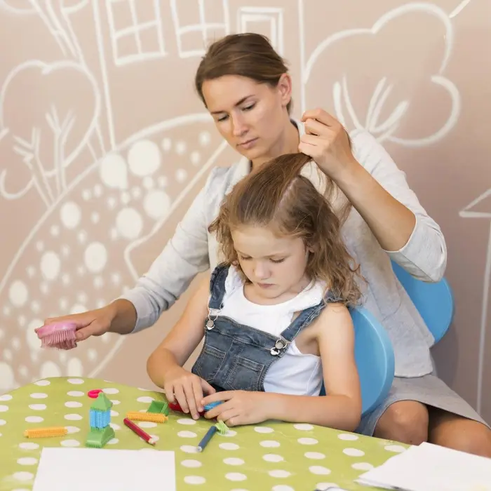 Une professionnelle de la garde d'enfants coiffe les cheveux d'une fillette.