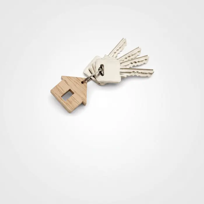 Un trousseau de clés avec un porte-clés en bois en forme de maison, illustrant l'aide au logement.