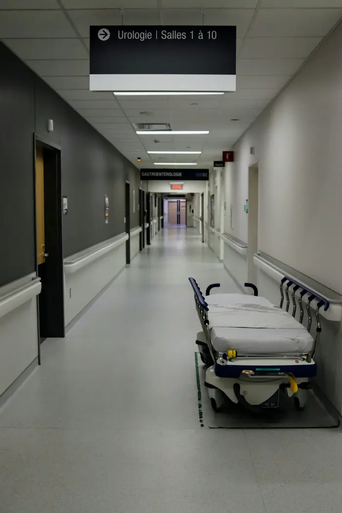 Un couloir d'hôpital vide avec un brancard stationné le long du mur.